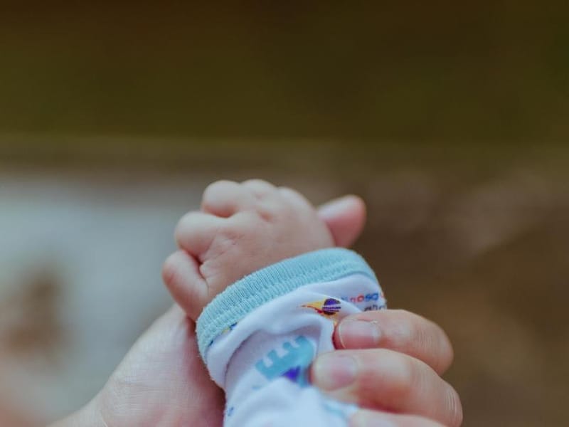 Tangan bayi menggenggam jari orang tua