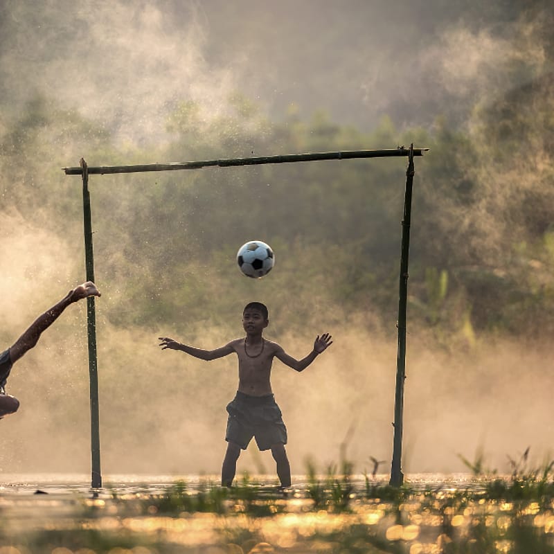 Anak-anak bermain bola di lapangan desa