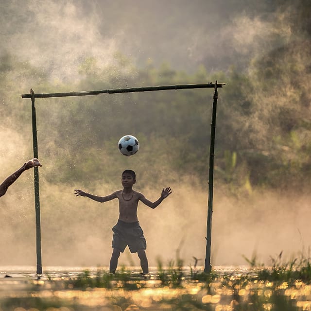 Anak bermain bola di lapangan desa