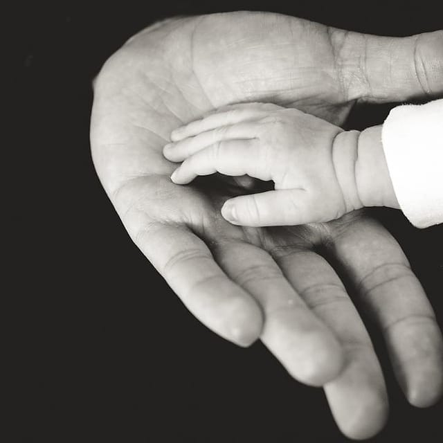 Tangan bayi di telapak tangan orang tua