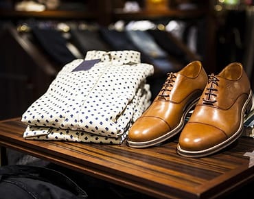 Kemeja dan sepatu kulit di rak toko