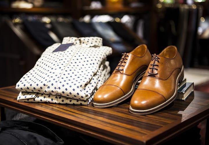 Kemeja motif dan sepatu kulit di meja toko