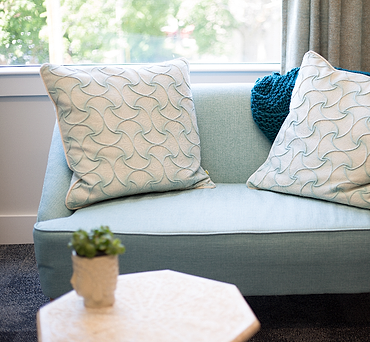 Sofa dua dudukan biru pastel dengan bantal motif