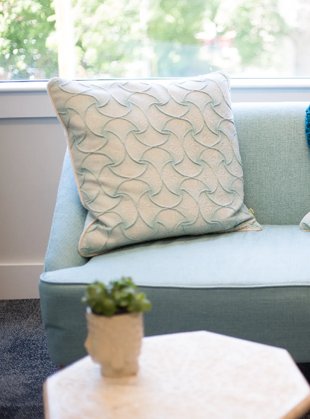 Sofa hijau toska dengan bantal bermotif