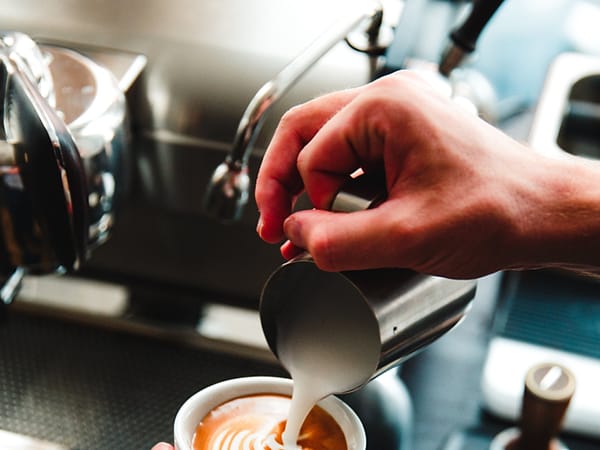 Barista menuang susu ke latte