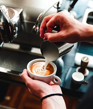 Barista menuang susu ke latte