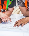 Dua orang membahas gambar kerja