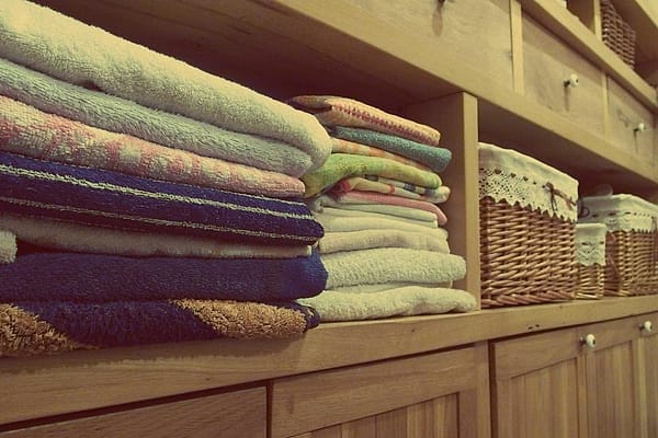 Handuk dan linen terlipat rapi di rak kayu