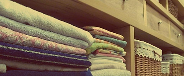 Handuk dan sprei terlipat di rak