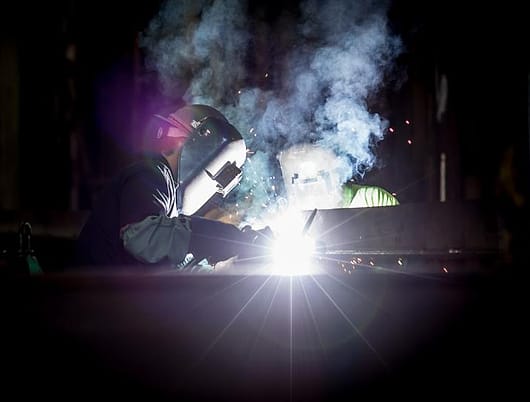 Pengelasan komponen baja di bengkel fabrikasi