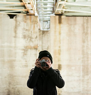 Fotografer dengan kamera di depan dinding beton