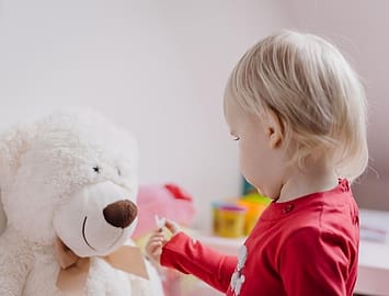 Anak balita bermain boneka