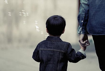 Anak berjalan sambil menggandeng tangan orang tua
