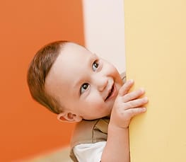 Bayi tersenyum mengintip dari balik dinding