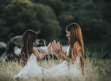 Dua anak bertepuk tangan di padang rumput